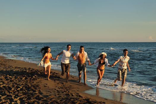 happy young people group have fun white running and jumping on beacz at sunset time