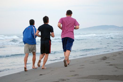 three friends jogging at beach