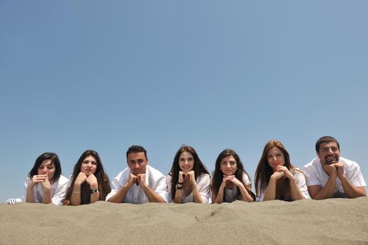 Group of happy young people in circle at beach have fun