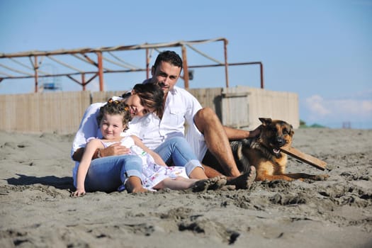 happy young family in white clothing have fun and play with beautiful dog at vacations on beautiful beach 