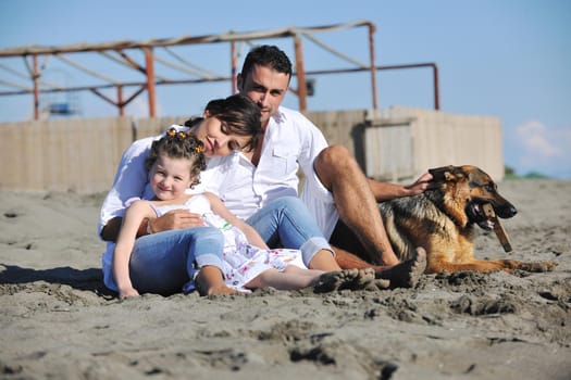 happy young family in white clothing have fun and play with beautiful dog at vacations on beautiful beach 