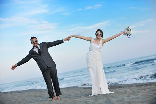 happy just married young couple celebrating and have fun at beautiful beach sunset