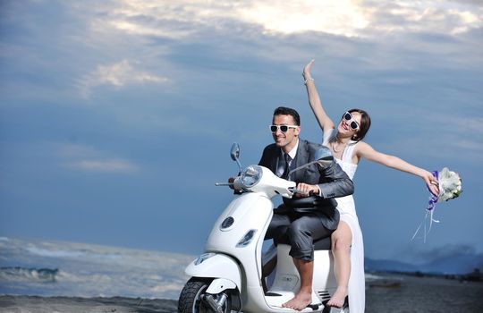 wedding sce of bride and groom just married couple on the beach ride white scooter and have fun