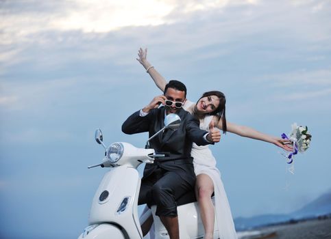 wedding sce of bride and groom just married couple on the beach ride white scooter and have fun