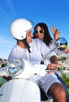 Portrait of happy young love couple on scooter enjoying themselves in a park at summer time