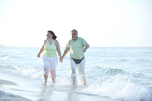 happy senior mature elderly people couple have romantic time on beach at sunset 