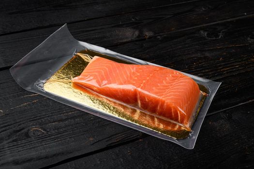 Raw salmon vacuum sealed bag for sell set, on black wooden table background, with copy space for text