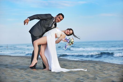 happy just married young couple celebrating and have fun at beautiful beach sunset