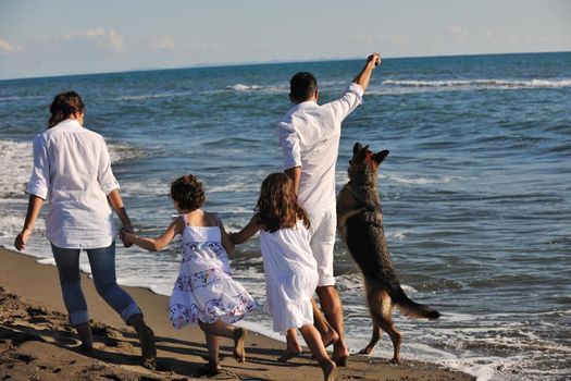 happy young family in white clothing have fun and play with beautiful dog at vacations on beautiful beach 