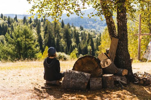 Woman next to logs of cut wood