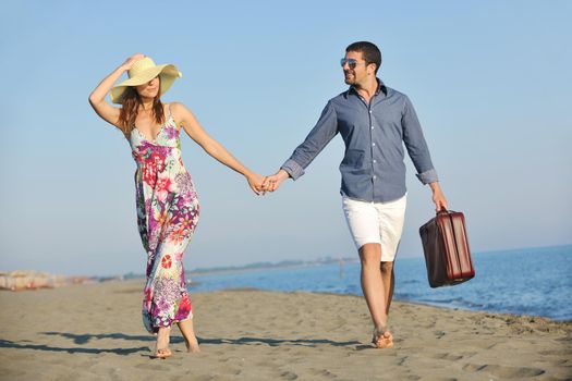 couple on beach with travel bag representing freedom and funy honeymoon concept