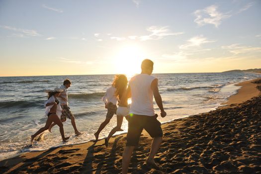 happy young people group have fun white running and jumping on beacz at sunset time