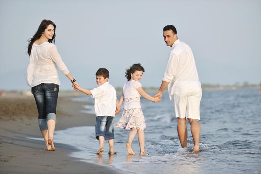 happy young family have fun on beach run and jump  at sunset