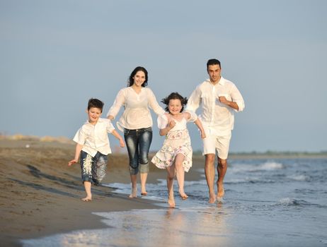 happy young family have fun on beach run and jump  at sunset