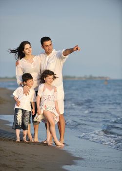 happy young family have fun on beach run and jump  at sunset