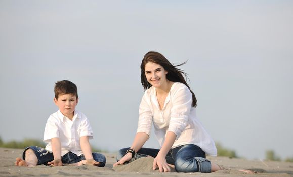 happy young mother  and son relaxing and play ind sand games on beach at summer season