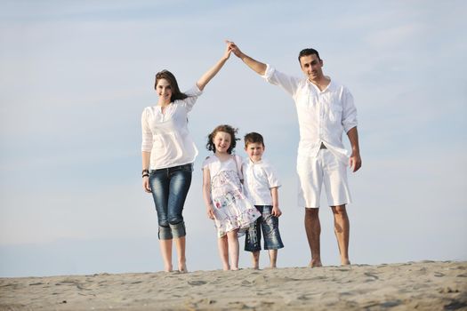 happy young family have fun on beachand showing home sign with conncected hands while protecting childrens