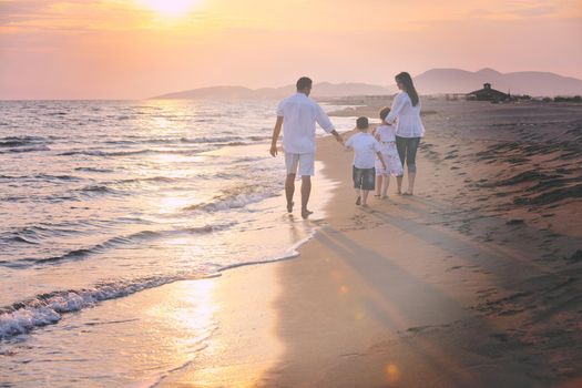 happy young family have fun on beach run and jump  at sunset