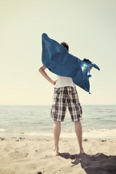 funny superhero standin at beach on hot sand