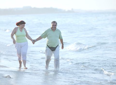 happy senior mature elderly people couple have romantic time on beach at sunset 