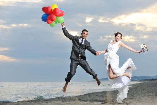 happy just married young couple celebrating and have fun at beautiful beach sunset