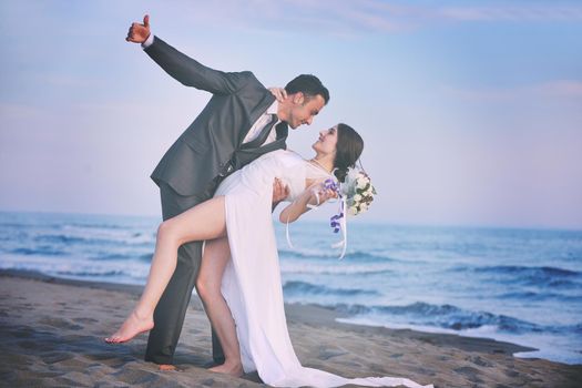 happy just married young couple celebrating and have fun at beautiful beach sunset