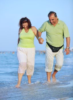 happy senior mature elderly people couple have romantic time on beach at sunset 