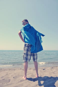 funny superhero standin at beach on hot sand