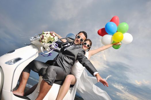 wedding sce of bride and groom just married couple on the beach ride white scooter and have fun