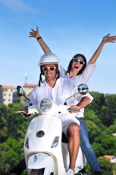 Portrait of happy young love couple on scooter enjoying themselves in a park at summer time