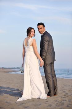 happy just married young couple celebrating and have fun at beautiful beach sunset