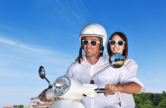 Portrait of happy young love couple on scooter enjoying themselves in a park at summer time