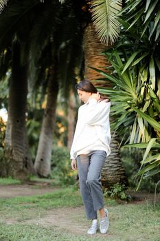 Chinese woman walking in tropical park and standing near palms. Concept asian beauty and nature.