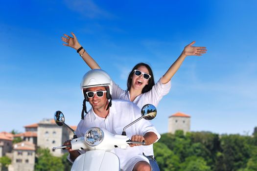 Portrait of happy young love couple on scooter enjoying themselves in a park at summer time