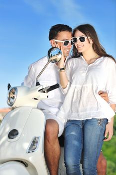 Portrait of happy young love couple on scooter enjoying themselves in a park at summer time