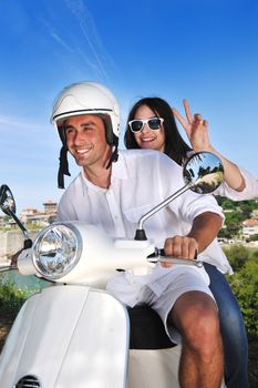 Portrait of happy young love couple on scooter enjoying themselves in a park at summer time