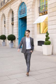 Young european man walking in city and wearing grey suit. Concept of fashion and businessman.