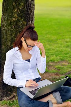 happy young student woman with laptop in city park study