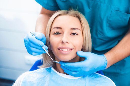 Dentist examinating blond girl with tools