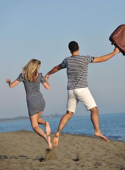 couple on beach with travel bag representing freedom and funy honeymoon concept