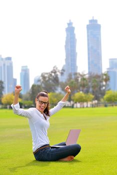 happy young student woman with laptop in city park study