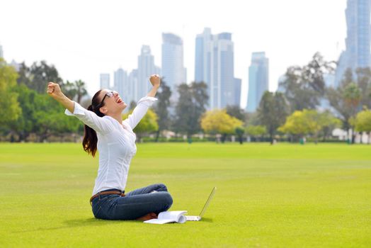 happy young student woman with laptop in city park study