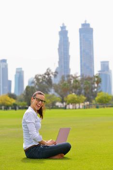 happy young student woman with laptop in city park study