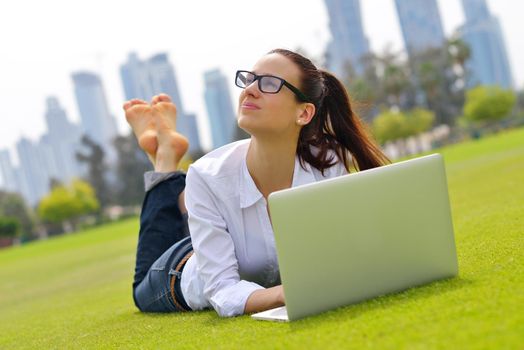 happy young student woman with laptop in city park study