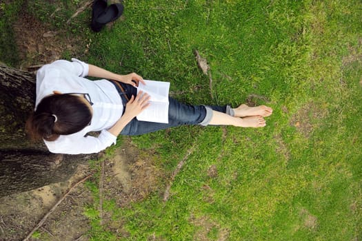 Young student woman reading a book and study in the park