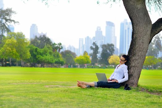 happy young student woman with laptop in city park study