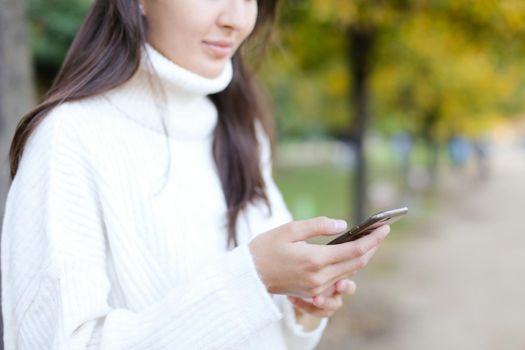 Brunette woman walking in park and chatting by smartphone. Concept of modern technology and strolling in park with mobile phone.