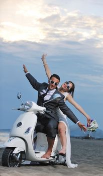 wedding sce of bride and groom just married couple on the beach ride white scooter and have fun