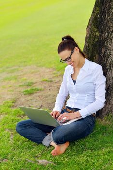 happy young student woman with laptop in city park study