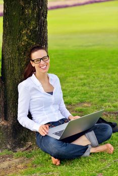 happy young student woman with laptop in city park study